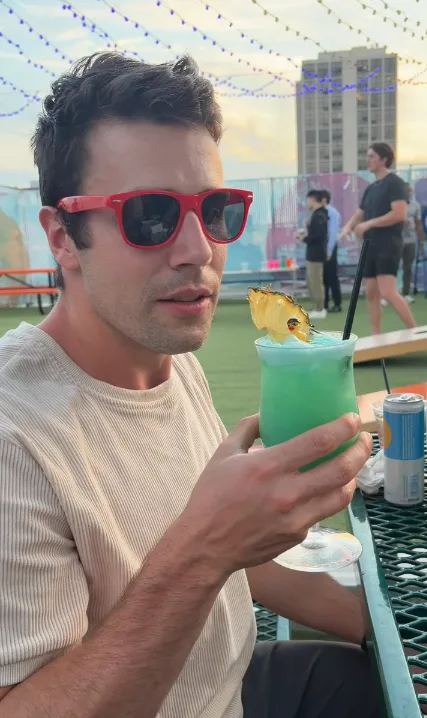 Cam trying a colorful drink at a Chicago rooftop